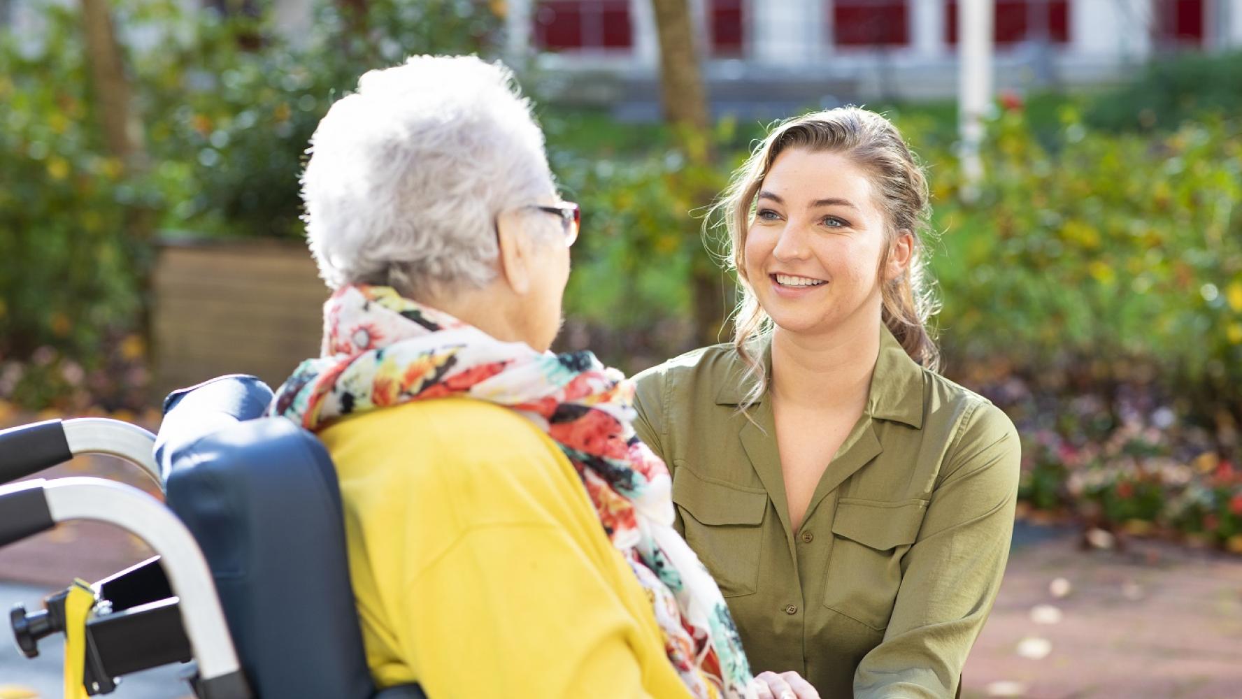 Medewerker met bewoner in rolstoel